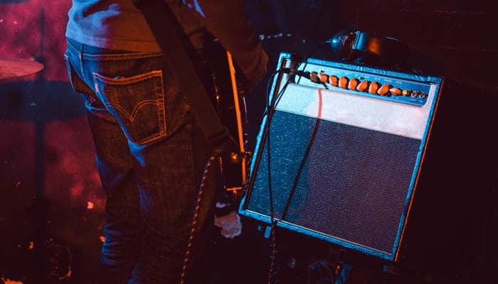 Person playing guitar with amp