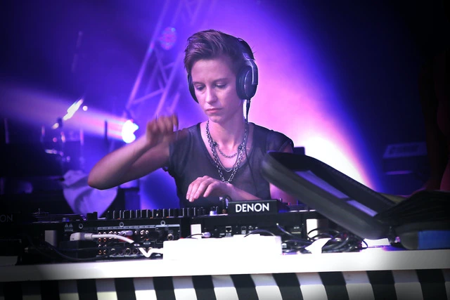 A picture of a DJ performing with headphones.