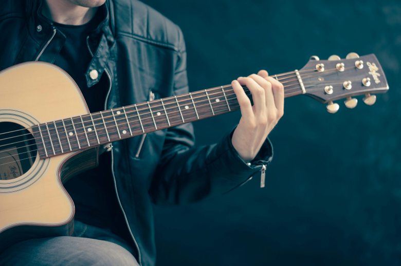 person holding brown and black guitar