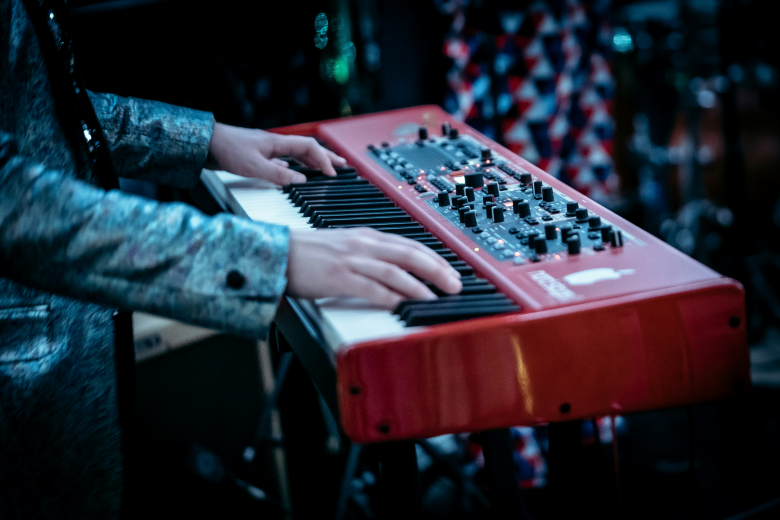 person playing a red synthesizer keyboard