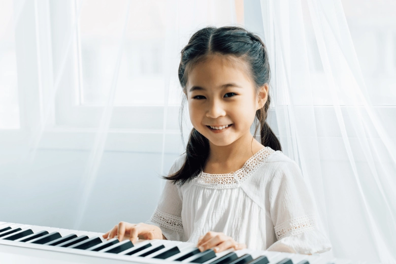 A little girl happily playing the electric piano.