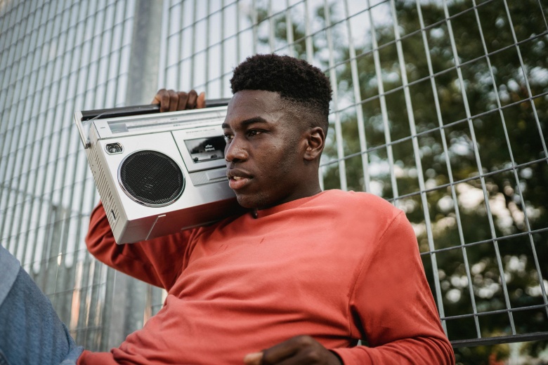 man leaning against fence with boombox on shoulder