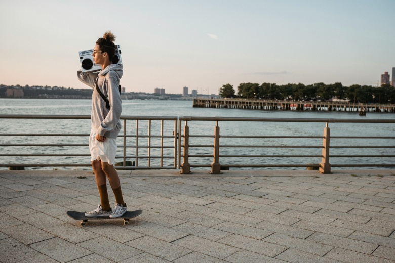 man skateboarding with a boombox by the waterfront