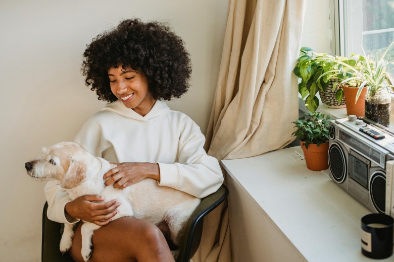 woman sitting with dog near window and boombox