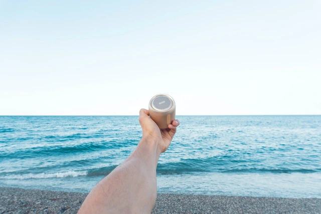 holding a small bluetooth speaker