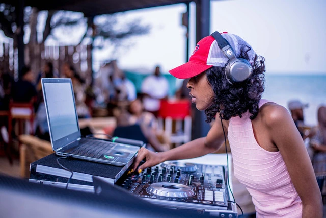 A DJ wearing a pair of DJ headphones and using a sound mixer.